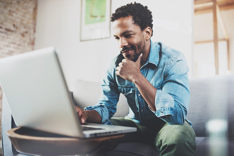Man smiling while looking at laptop screen